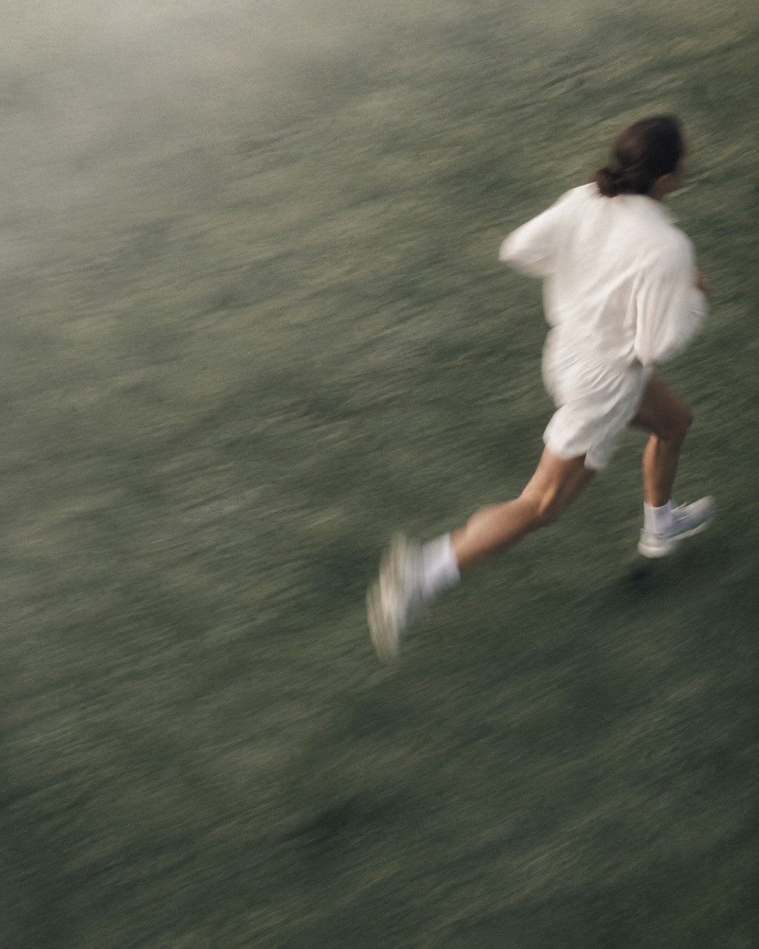 A runner in white crossing a grassy field